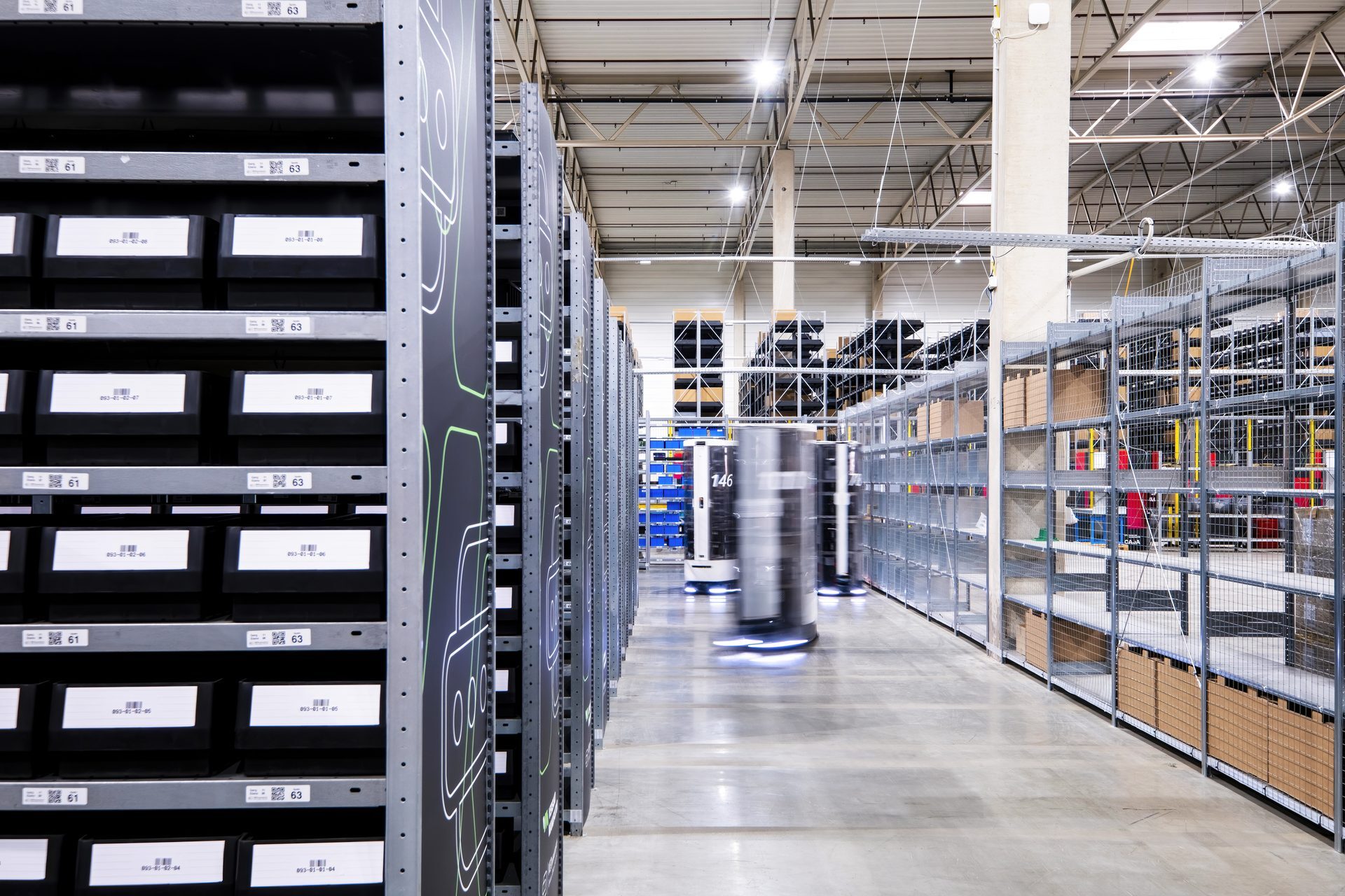 Autonomous mobile robot moving through a warehouse aisle