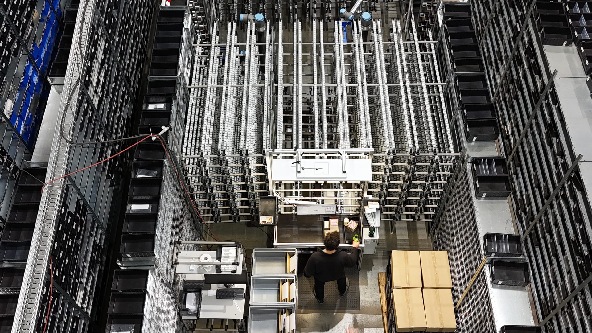 Kommissionierstation aus der Vogelperspektive mit Operator am Arbeitsplatz und Pushback-Compartments als Behälter-Zwischenspeicher